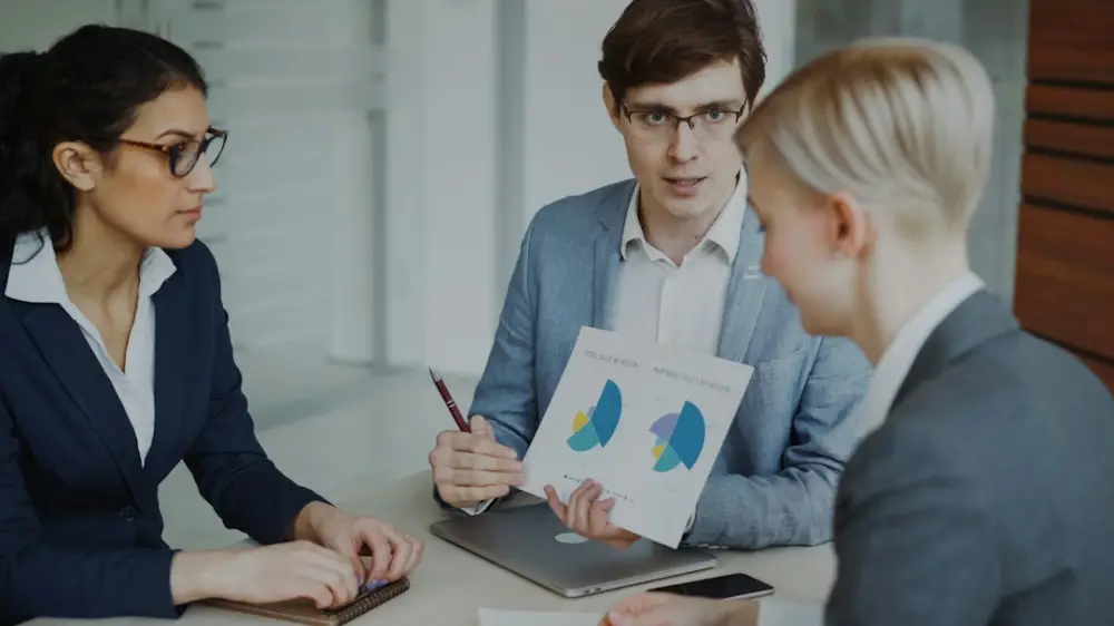 Three professionals discussing charts in a meeting, illustrating credential judgment